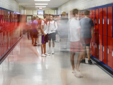School Hallway with students standing in front of red lockers